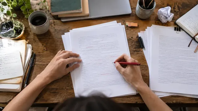 Mains relisant et corrigeant des pages de manuscrit au stylo rouge
